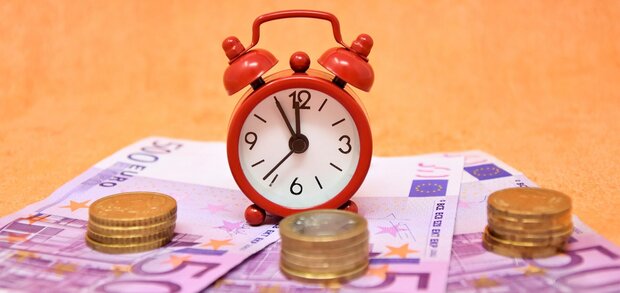 Drei 500-Euronoten und etwas Münzgeld liegen aufgefächert, ein Wecker wurde darauf platziert